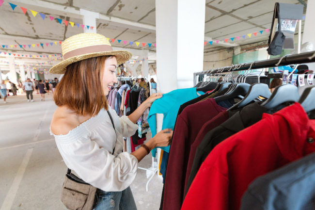 Asian woman customer choosing clothes in a shop. Happy purchase and shopaholic concept