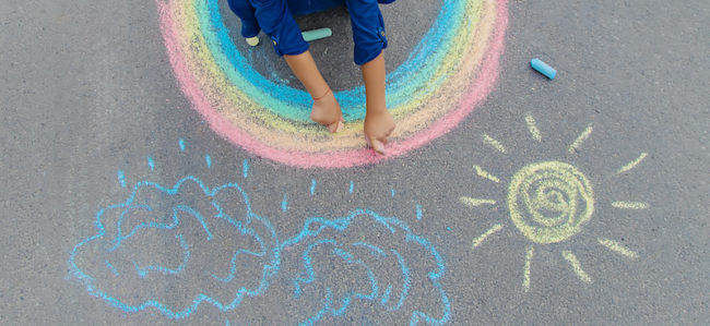 child draws with chalk on the pavement. Selective focus.